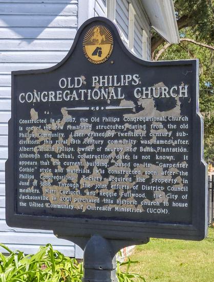 Close up of historical marker: 

Constructed in c. 1887, the Old Philips Congregational Church is one of the few remaining structures dating from the old Philips Community. Later erased by twentieth century sub-divisions, this rural 19th century community was named after Albert Gallatin Philips, owner of nearby Red Bank Plantation. Although the actual construction date is not known, it appears that the current building, based on its "Carpenter Gothic" style and materials, was constructed soon after the Philips Congregational Society acquired the property in June of 1886. Through the joint efforts of District Council members, Matt Carlucci, and Reggie Fullwood, the City of Jacksonville in 2001 purchased this historic church to house the United Community of Outreach Ministries (UCOM).