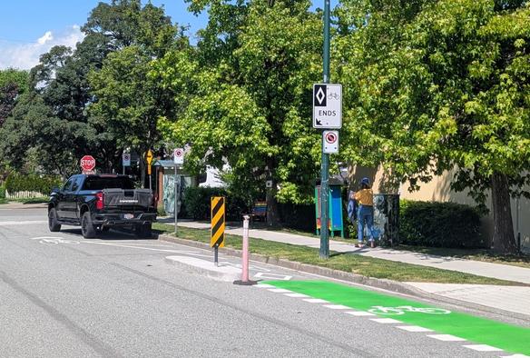 a bike lane that ends and requires cyclists to merge with the rest of traffic before the intersection, allowing 1 parking spot (with a large puckup truck parked in it)