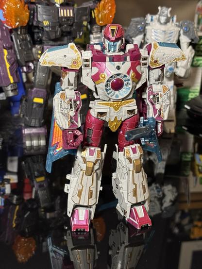 Transformers Legacy Vector Prime with the Toyhax stickers and leg parts applied, posed in robot mode on a black table with other Transformers robots in the background.