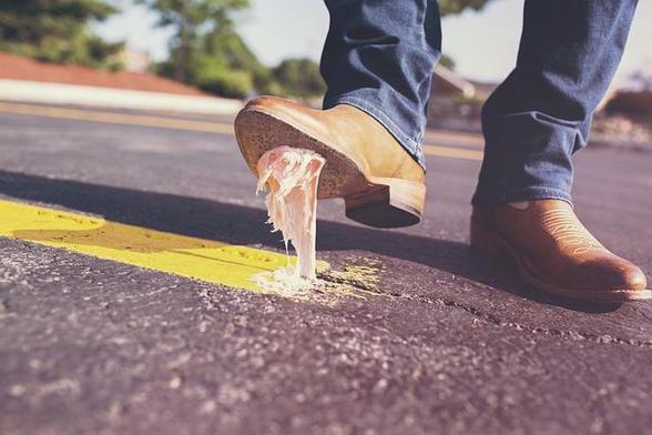 Bubble gum stuck to a workboot trying to pull up from the pavement.