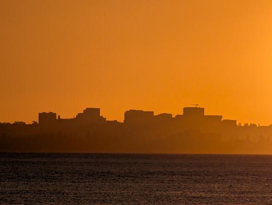 Urban skyline seen against an orange sunset sky