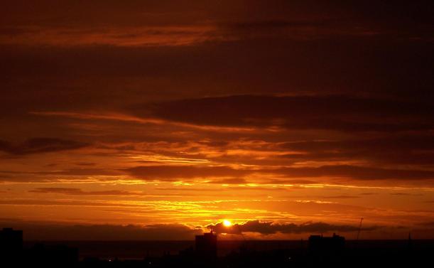 sunrise in aberdeen. black and gold sky with sun behind clouds