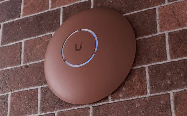 A Ubiquiti U7 Pro Access Poi.t with the optional, painable cover, showcasing the ability to hide it with a brick-red colour  painted over a (supposedly) brick wall to make it inconspicous.