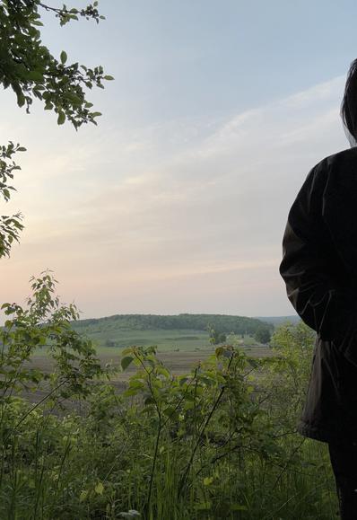 The sun is just up outside the frame of this picture. It’s glowing red almost to my eyes. Everything is a bit hazy. The air is mild. The fields and hills are green. I hear a wren and a crow. And I’m wearing a net over my hat down to my shoulders to deter the mosquitoes.