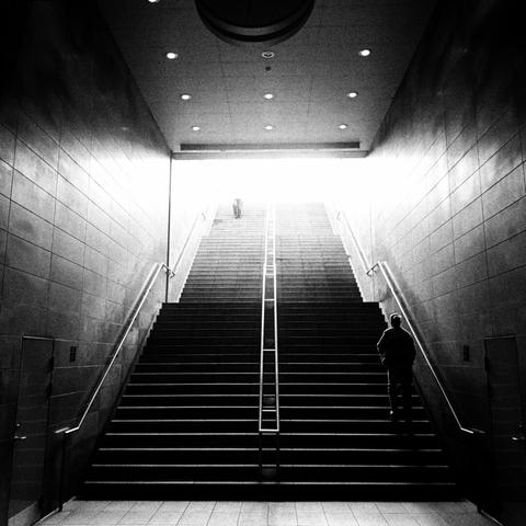 a subway staircase going up toward over exposed light.