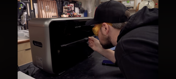 Person wearing tinted safety glasses (included) peering into the printer, which is not much larger than my Canon home office ink jet printer.