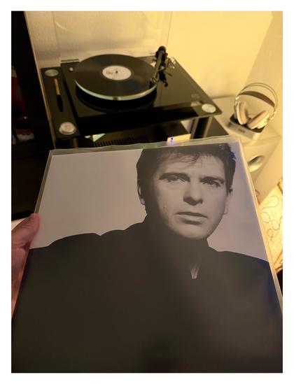 Auf einem schwarzen Plattenspieler läuft eine schwarze Schallplatte. Davor halte ich das Cover ins Bild. Ein schwarz-weiß Foto von Peter Gabriel.