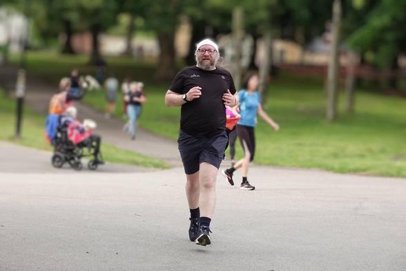 A runner dressed in black, heading towards the viewer. There are people behind him, blurred out.