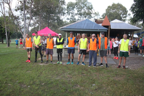 A bunch of guys in hi viz outfits pose for a photo ahead of Chermside parkrun