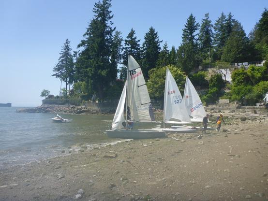 Boats sitting on the beach at West Bay Park. Three boats are on the beach, one is anchored.