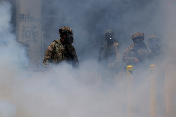 National Guard troops in gas masks stand in a thick cloud of tear gas. REUTERS/Daniel Cole