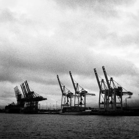 the cranes of the hamburg harbour from the elbe river, in grainy black and white