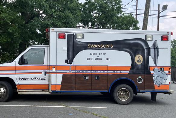 photo: 

Kathryn Swanson recently bought a used box-truck style ambulance to create a Fabric Rescue and Mobile Mending Unit. A large painting of a very old black Singer sewing machine is on the side. The “Singer” logo on the arm is replaced with: “Swanson’s”. Just below the sewing machine arm is the text: “FABRIC RESCUE MOBILE MENDING UNIT” and below in smaller block lettering is: “MOM HAVE TOO MUCH GABRIC OR YARN    WE CAN HELP”