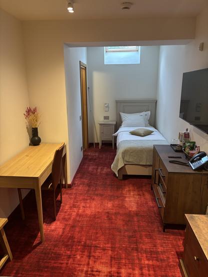 Single room with bed and other furniture. Light is via a skylight.
