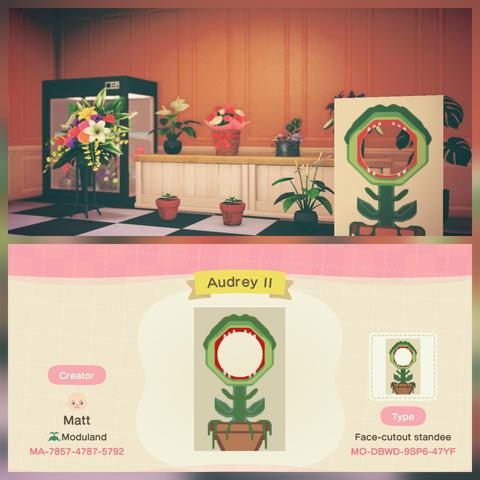 Collage of two Animal Crossing: New Horizons screenshots stacked vertically. The upper image shows a flower shop with orange walls and a white counter. On and around the counter are assorted plants with a black flower case on the left. On the right near the front is a standee with an image of a carnivorous plant with a red mouth open and little white teeth that is sitting in a large pot. The bottom image is a custom design screen entitled "Audrey II" which has a face cutout standee that has a thick trunked plant with a wide open mouth with teeth. It is read around the mouth and the plant is sitting in a brown planter with vines coming down. It is intended to look like Audrey II from Little Shop of Horrors. The custom design ID is MO-DBWD-9SP6-47YF.