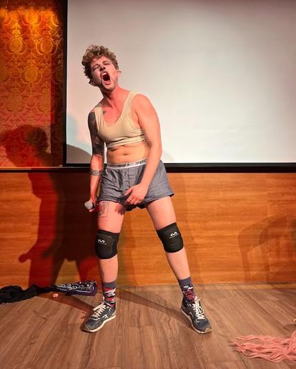 Person on stage with knee protectors. Eyes are closed while mouth is wide open for a scream.