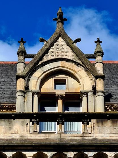 An ornately shaped dormer window on a Victorian financial building in Glasgow.