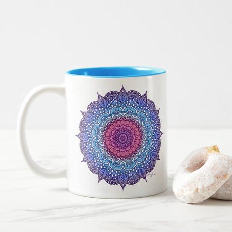 product image of a mug on the sides are a flower like mandala design in pink, light blue, blue, and purple, the inside and rim of the mug have been glazed in light blue to match the mandala.