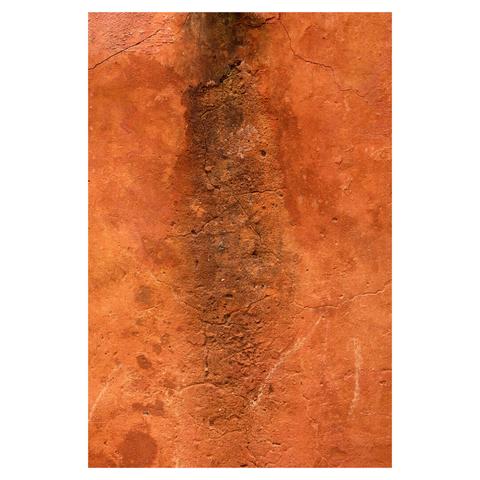 Flat closeup of an ochre-coloured wall. The wall has a rough texture and is cracked in multiple places. In the center of the frame, a darker patch is visible where water has seeped in.