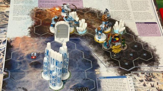 An open Frosthaven scenario booklet, decorated with ice pillars and smaller ice crystals. Four player minis face off against five icy monster minis. Algox are brutish, horned, massive, furry people and they don't like us much.