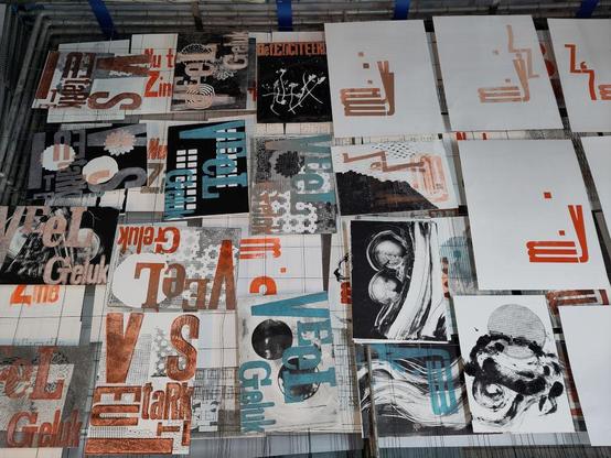 A drying rack full of colorful prints on A5 paper. Some on A4. Large letters in orange on black and gray textures. Similar but with turquoise type. Lots going on.