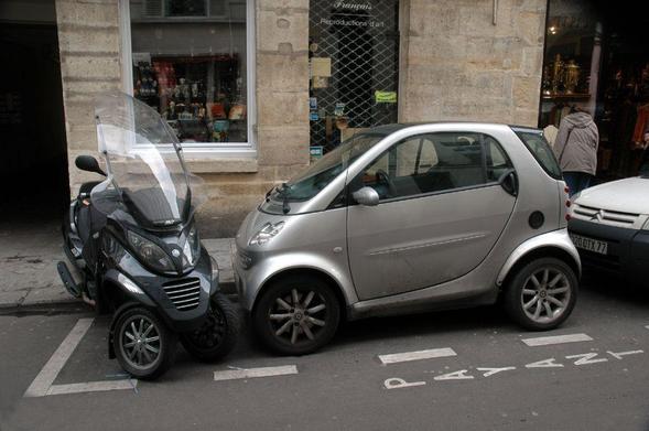 small meetings: photograph of two tiny vehicles parked in one parking space. Photo attribution: Flickr user caribb