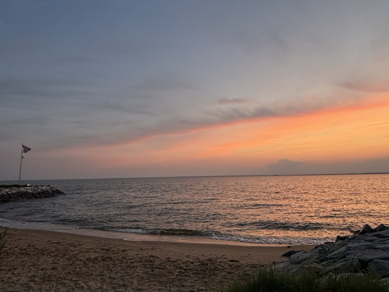 Chesapeake bay beach  at sunset. The sky is blue, purple, and orange as the sun dips below the horizon.