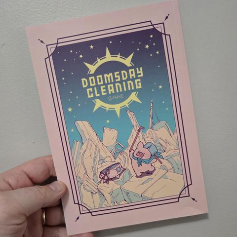 A white person's hand holding up a book entitled Doomsday Cleaning. The cover has a pink background with a purple elaborate rectangle around a central image. The image says the title of the manga in the center with what looks like a self-propelled vacuum cleaner, like a Roomba, standing on rocky ground next to a pig standing on its hind legs holding a pole while wearing a cape and a pot on its head. The sky behind them is dark, but full of stars.