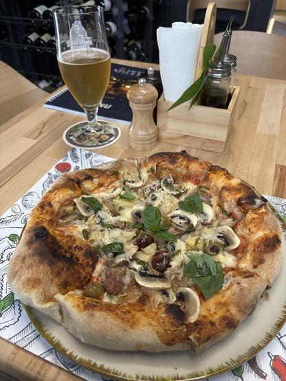 Pizza on a plate, with a glass of beer next to it.