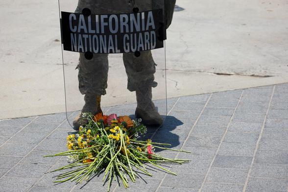 Flowers lie in front of a California National Guard standing guard outside the Edward R. Roybal Federal building.