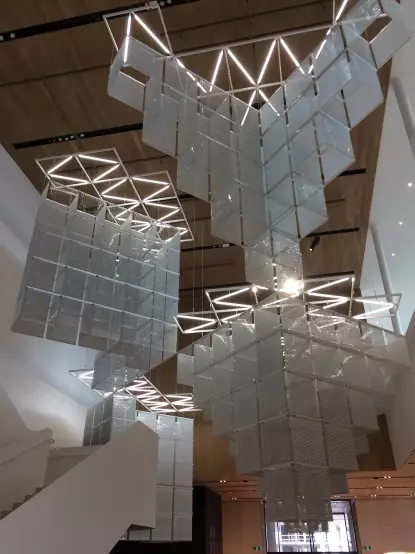 The image features a modern architectural design with large, sculptural hanging light installations. These structures appear to be made of transparent or translucent materials, creating a visually striking effect. The overall space seems to have a clean and contemporary aesthetic, with wooden ceilings and a mix of lighting that enhances the design elements.

Image Credits: Wikimedia / daryl_mitchell from Saskatoon, Saskatchewan, Canada / CC BY-SA 2.0