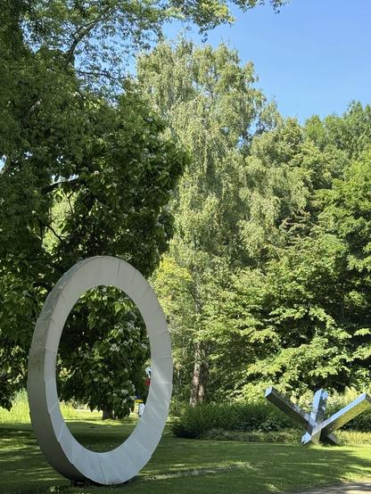 Zwei Skulpturen Open Air. Eine sieht aus wie ein „O“, die andere wie eine Panzersperre aus Chromstahl