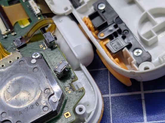 Photo of two shoulder buttons on a 2DSXL, one detached from the PCB and the other partially raised.
