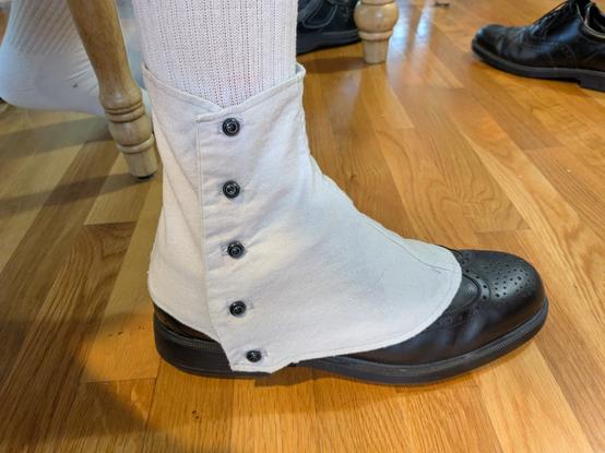 The ankle and foot of a man wearing a dress shoe and a spat.