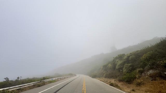 Derelict road turning into a brown hill at the horizon in thick fog