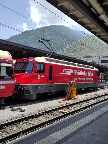 Foto. Eine rote Lokomotive im Bahnhof.