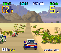 Captura de tela de jogo retrô, com carrinhos cruzando uma região desértica.