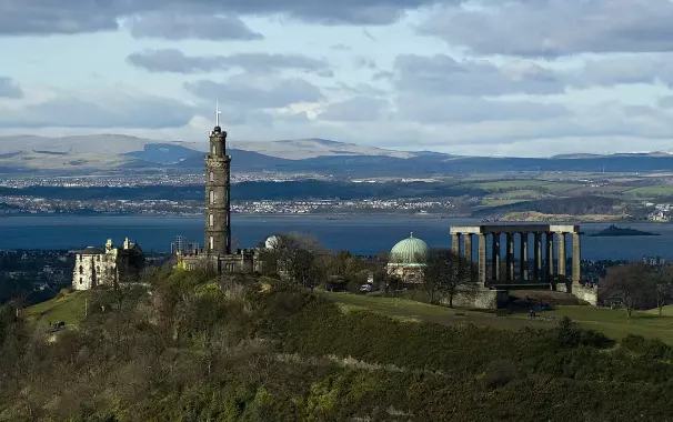 The image depicts a landscape featuring prominent architectural structures against a backdrop of water and hills. On the left, there is a tower, likely a monument, and other buildings can be seen nearby. To the right, there is a large classical-style structure with columns, often associated with ancient Greek or Roman architecture. The setting appears to be coastal with hills and mountains in the distance, suggesting a scenic location. Overall, it looks like a notable viewpoint or landscape.

Image Credits: Wikimedia / Saffron Blaze / CC BY 3.0