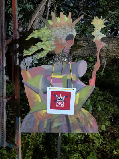 No Kings sign hanging from an abstract, outdoor art installation.