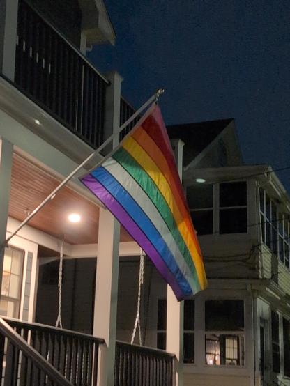 A Pride flag, waving in the wind outside a home.