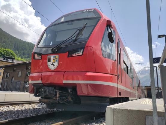Foto. Ein roter Zug im Bahnhof aus der Froschperspektive.