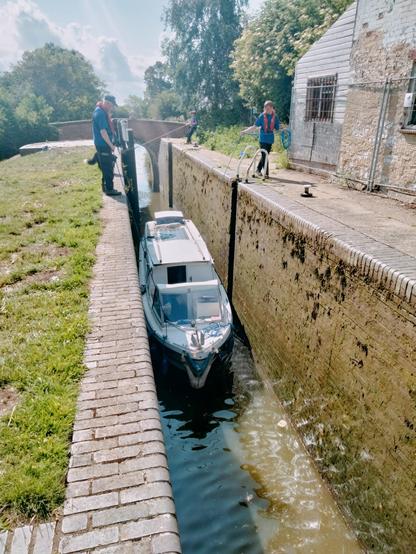 CRT volunteers roping a small GRP cruiser through Grant's Lock south of Banbury on the Oxford Canal.