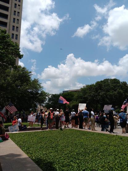 Another shot of folks on west seventh, but wider and in portrait, showing a helicopter hovering in the sky in the distance, presumably watching the protest.