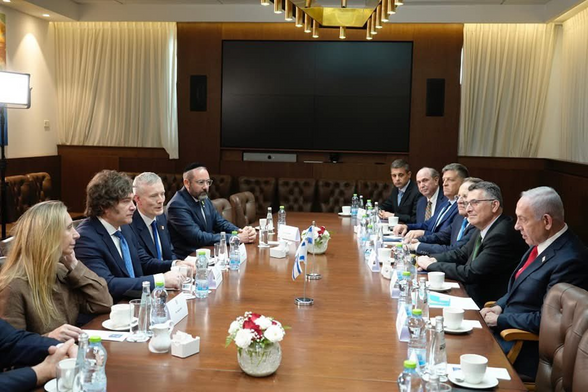 Benjamin Netanyahu has a map on south american patagonia region in front of him. in front of him is argentine president Milei and her sister. They are sitting around a huge table with many other people.