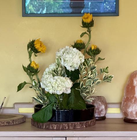 Moribana style arrangement with white hydrangeas and sunflowers.