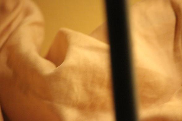 Yellow-toned image of fabric interrupted by a vertical line with slight diagonal tilt.