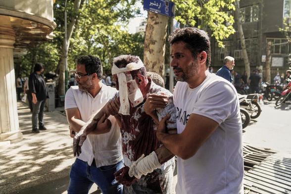 An injured man is led from the scene after an Israeli airstrike on downtown Tehran, June 15, 2025. (Amir Kholousi/ISNA/AP)