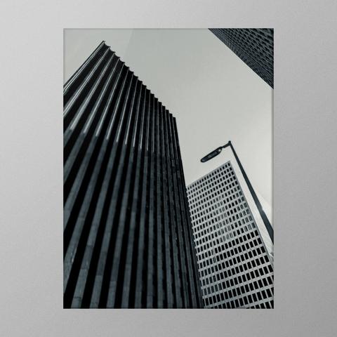 A black and white photo showing a low angle view of tall office buildings. Everything is straight lines.