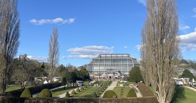 Panoramafoto des Großen Tropenhauses, einer prächtigen Glaskuppel, vor der sich viele Menschen tummeln