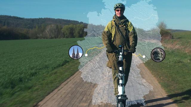Jan Böhmermann fährt mit einem E-Scooter durch eine Landschaft. Hinter ihm ist der Umriss einer Deutschlandkarte abgebildet.